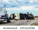 Small photo of Fifth wheel RV overturned on highway with wench truck trying to get it off the road and two semis parked nearby and traffic cones keeping traffic away