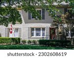 Small photo of Nov 2017 Tulsa USA - Landscaped grey painted brick house entry with Canadian flag and OU sooner football plaque