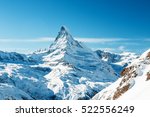 Scenic view on snowy Matterhorn peak in sunny day with blue sky and some clouds in background, Switzerland.