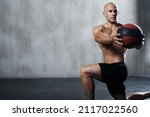 Great gym session in progress. Shot of a man working out with a medicine ball at the gym.