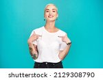 Small photo of Make it your own. Studio shot of a confident young woman pointing at her t shirt against a turquoise background.
