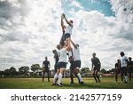 Reach for the sky. Shot of two rugby teams competing over a ball during a line out of a rugby match outside on a filed.
