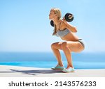 Lift with your legs. Full length shot of an attractive young woman doing squats with a barbell outside.