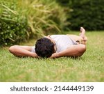 Taking time out to relax. A young man lying on the grass with his hands behind his head.