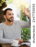 Small photo of Shoutout to the awesome coffee and wifi. Shot of a handsome young man gesturing to get someones attention at an outdoor cafe.