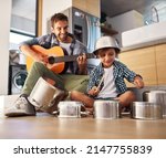 Small photo of Its a father-son collaboration. Shot of a happy father accompanying his young son on the guitar while he drums on a set of cooking pots.