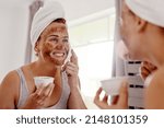 Small photo of I cant wait to see the beautiful results after this. Cropped shot of an attractive young woman applying a coffee mask on her face while standing in front of the mirror in her bathroom at home.