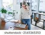 Small photo of Upholding a solid connection to success. Shot of a mature businesswoman talking on a cellphone while using a digital tablet in an office.