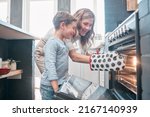 Small photo of Cooking and baking is both physical and mental therapy. Shot of a little boy and his mother sitting in front of the oven.
