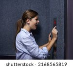Small photo of Is anyone out there. Shot of a fearful woman shouting into an elevator intercom.