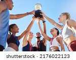 Small photo of A diverse team of athletes celebrating a victory with a golden trophy and looking excited. A fit and happy team of professional athletes rejoicing after winning an award at an athletic sports event