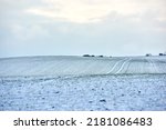 Small photo of Countryside landscape on a cold winter day with cloudy sky background and copy space. Nature landscape of a farm field, meadows or grass land covered in white snow on a bright overcast morning