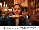 Hungry woman with delicious pizza, food or consumables at a bar, restaurant or diner at night. One happy and casual girl, foodie or tourist enjoying a dinner meal at a local trendy location