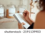 Budget planning, making shopping list and managing household expenses to save money. Financial accountability at home. Woman making shopping list for groceries on a notebook to plan a meal for