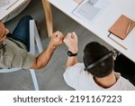 Excited call centre agents, fist bump and celebrating deal, promotion and sale from above in office. Motivated, happy and successful telemarketing colleagues or customer support operators cheering