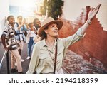 Travel, education and a teacher with students on school field trip, on urban tour. Woman, city guide and group of happy tourists, pointing at local architecture and learning on international holiday