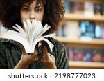 Scholarship, books and girl student in library learning, studying and reading educational knowledge or information. Young, smart and afro black woman on university or college campus with school novel