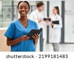 Small photo of Portrait of happy woman doctor working on a digital tablet and smile while working at a hospital. Black female nurse doing medical and healthcare research on the internet or online at work at clinic