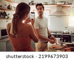 Small photo of Cooking man sticking out tongue to make silly, goofy and funny face to pose for a photo while making food in the kitchen at home. Crazy, fun and happy couple enjoying a playful moment while bonding