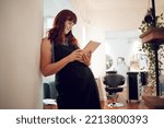 Small photo of Salon, tablet and schedule with a woman hairdresser checking her appointment or online booking. Calendar, technology and stylist with a female worker or small business owner in the hair care industry