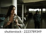 Small photo of I think that guy is following me.... A young woman in a parking lot looking concerned as someone follows her.