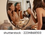 Mirror, beauty makeup and friends at party getting ready for new year celebration. Event, skincare cosmetics and happy women preparing for fun social gathering at night with lipstick at house party.