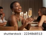 Champagne, celebration and happy black woman at a party or dinner at a table in the dining room. Happiness, smile and African lady enjoying a glass of alcohol beverage at a new year event at a house.