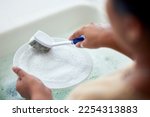Small photo of Cleaning kitchen, soap water and hands of woman cleaner to clean plate with a brush for hygiene. Maid service for washing dishes to wash away bacteria, dirt or virus in house, home or apartment