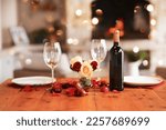 Small photo of Romantic, dinner table and setup for valentines day, fine dining or date at indoor night restaurant. Interior diner with wine glasses prepared with roses and champagne for evening couple reservation