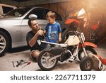 Small photo of Being a role model to his little boy. Shot of a father and son fixing a bike in a garage.