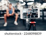 Small photo of Gym, social media and fitness influencer with phone live streaming workout for interactive multimedia broadcast. Vlog, man filming arm exercise and training coach video recording online blog tutorial