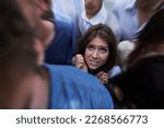 Small photo of Drowning in people. Shot of a fearful young woman feeling trapped by the crowd.