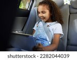 Small photo of Child in car, tablet and video on road trip with seatbelt for safety and device to play educational online game. Technology, internet browsing and travel, happy girl on backseat for drive or carpool.
