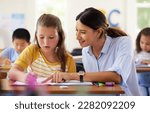 Small photo of Teacher, learning and helping girl in classroom for writing, studying or assessment. Teaching, development and kid or student with happy woman for education assistance with notebook in kindergarten.