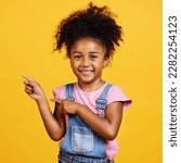 Small photo of Portrait, studio and happy child pointing hand at space with a smile on face on yellow background. Young girl kid with happiness, carefree and positive attitude to show product placement mockup deal