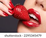 Beauty, makeup and woman with a strawberry in a studio with red nails and lipstick cosmetics. Health, wellness and closeup of a female model eating fruit for nutrition isolated by a gray background.
