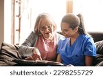Small photo of I have so many stories in here. a nurse and a senior woman looking at a photo album together.