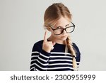 Strict, serious and portrait of a child with a gesture isolated on a white background in a studio. Rude, smart and a young girl wearing glasses and gesturing with finger for discipline on a backdrop