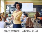 Small photo of Portrait, black woman and teacher with arms crossed, students or happiness in a classroom. Face, female educator or employee with children, smile or education with knowledge, learners and development