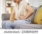 Small photo of Sick woman, sofa and stomach pain for health, digestion and nausea of pms at home. Closeup of female person, menstruation and abdomen bloating of constipation, period and endometriosis in living room