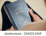 Small photo of Bible, hands and person in prayer, religion and peace in a lounge, praise and holy worship for guidance. Closeup, believer or faith with meditation, reading book or mindfulness with spiritual or calm