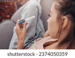 Small photo of Pregnancy test, waiting and woman on sofa in home, reading news and check results.,Stick, sad and pregnant mother in living room for future maternity, ivf fertility and anxiety, depressed or serious
