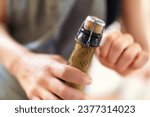 Small photo of Hands, person and open cork on bottle of wine, champagne and alcohol for party, celebration and congratulations for special event. Closeup, drink and pop muselet, wire cage and cap of liquor beverage