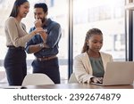 Office bully, woman and working at laptop with coworkers laughing in a corporate workplace about gossip. Young black person typing on a computer with internet and joke with staff being mean at desk
