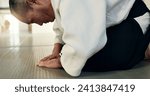 Small photo of Asian man, student or bow in dojo for respect, greeting or honor to master at indoor gym. Closeup of male person or karate trainer bowing for etiquette, attitude or commitment in martial arts class