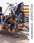 Small photo of Motorbike, race and sports with man getting ready for off road adrenaline, competition or training outdoor. Boots, adventure and dirtbike hobby with person in gear on trailer for performance