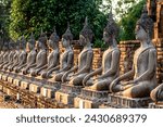 Small photo of Wat Yai Chai Mongkhon, Thailand - ancient Buddha statues in the waning sunset light, with red brick background