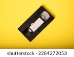Small photo of Movie Night - Video Tape on Yellow Background. VHS Tape, a staple of an age before streaming, when movie rental stores were a necessary element of watching a movie at home.