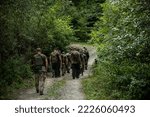 Small photo of military platoon soldiers are walking along the road in the forest. a group of people in military uniform on their way to battle. military of Ukraine. war in Ukraine. general plan
