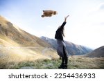 a hipster girl in a dress and black shoes throws a big teddy bear into the air against the background of mountains. a woman holds her hands up and catches a bear toy. Transfagarash mountains